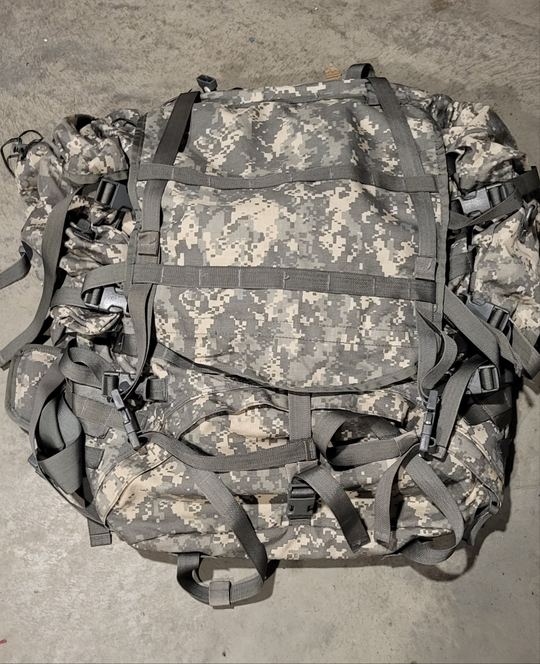 Camouflage backpack with multiple straps on a concrete surface