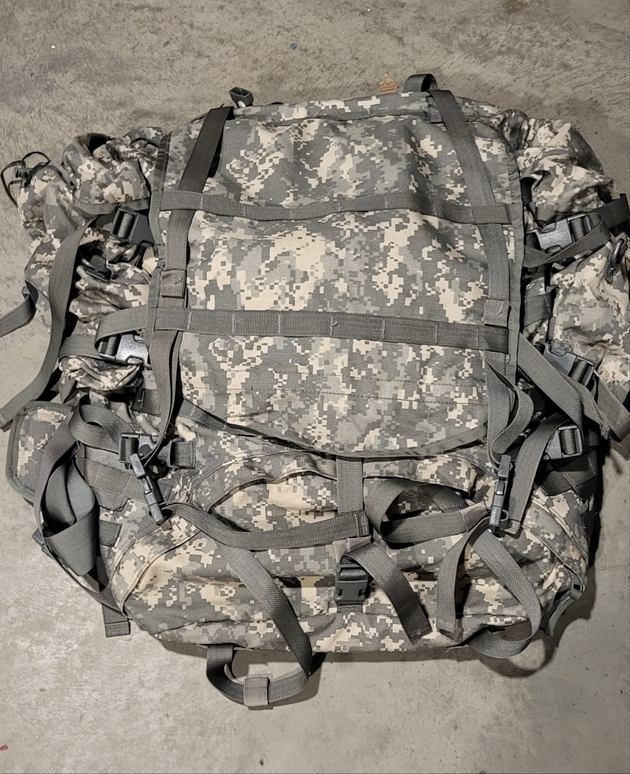 Camouflage backpack with multiple straps on a concrete surface