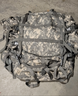 Camouflage backpack with multiple straps on a concrete surface