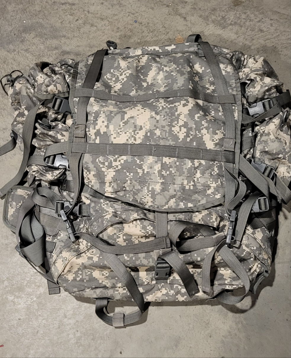 Camouflage backpack with multiple straps on a concrete surface